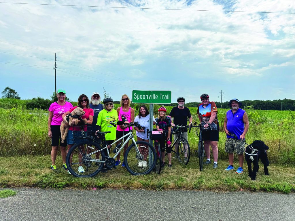 Group of cyclists with dogs on Spoonville Trail, ready for a biking adventure amidst nature.
