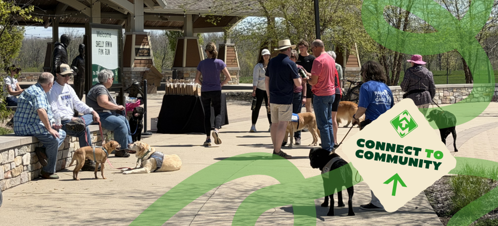 Community event with people and dogs outdoors at pavilion, featuring Connect to Community sign.